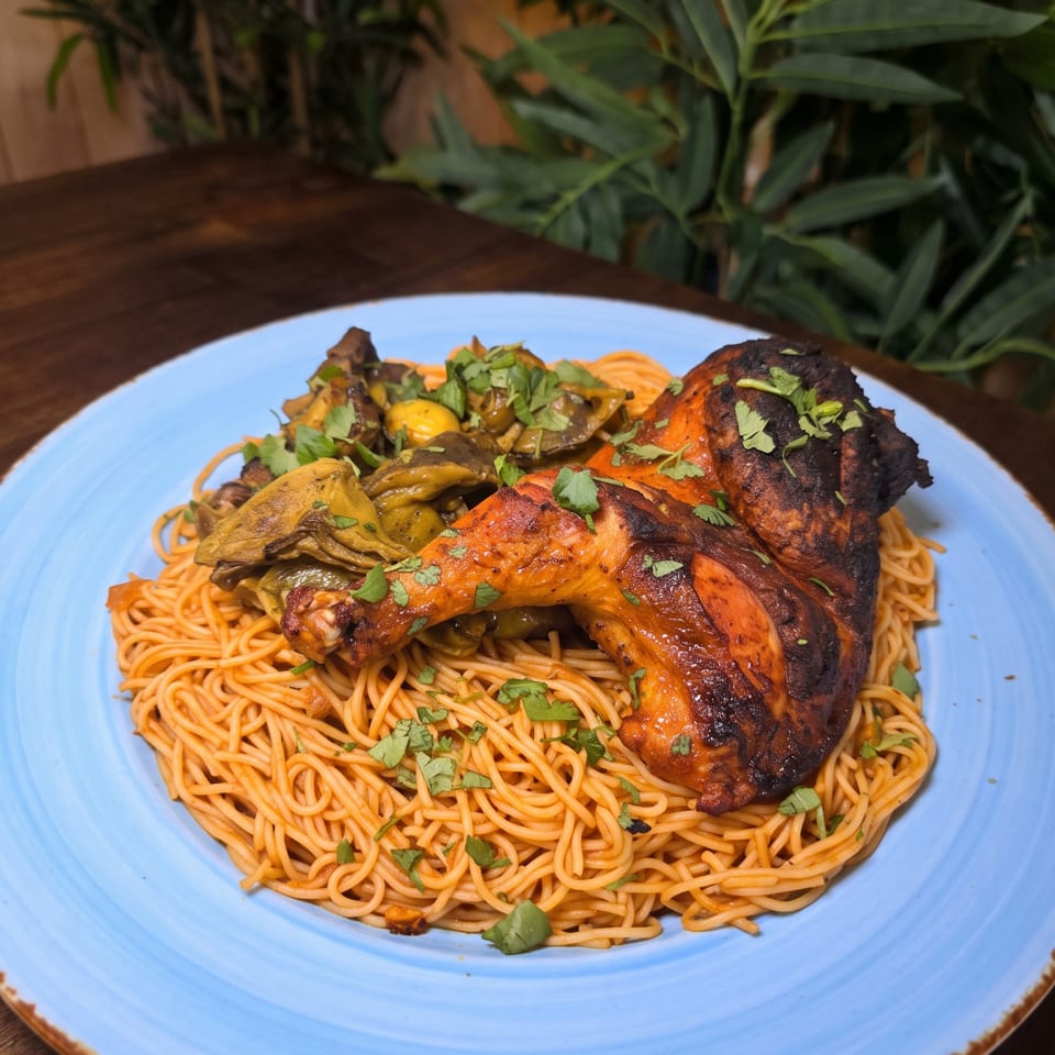 Grilled chicken legs and roasted vegetables served over saucy noodles, garnished with fresh cilantro on a blue plate.